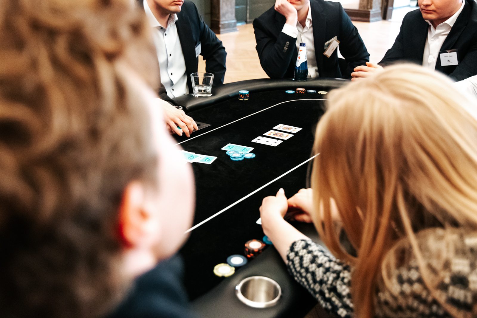 Pelaajat pokeripöydän ääressä, pöydällä kortit ja pelimerkit