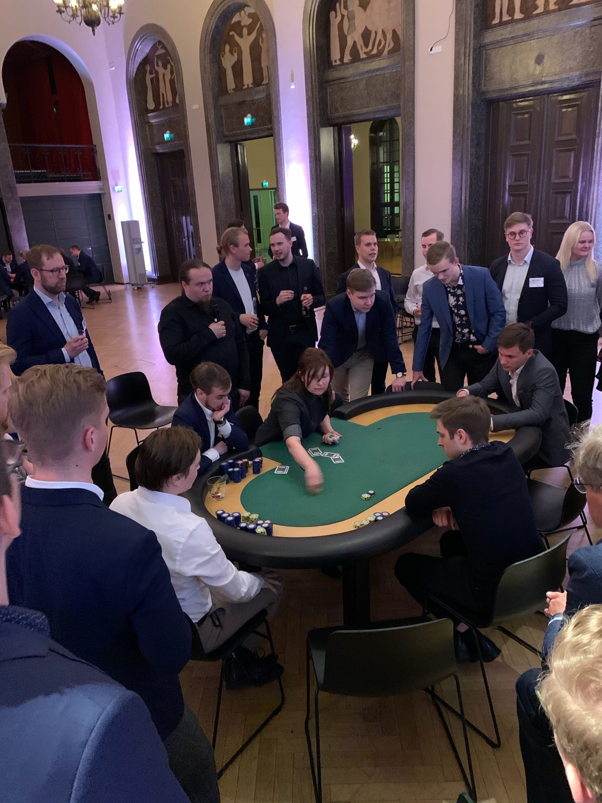 Pokeripeli vihreällä pöydällä, ympärillä yleisöä seuraamassa